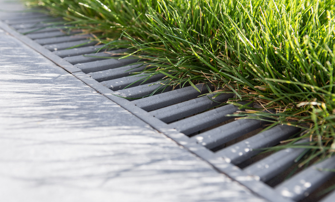 La grille du caniveau de drainage s'harmonise parfaitement avec les dalles de terrasse grises