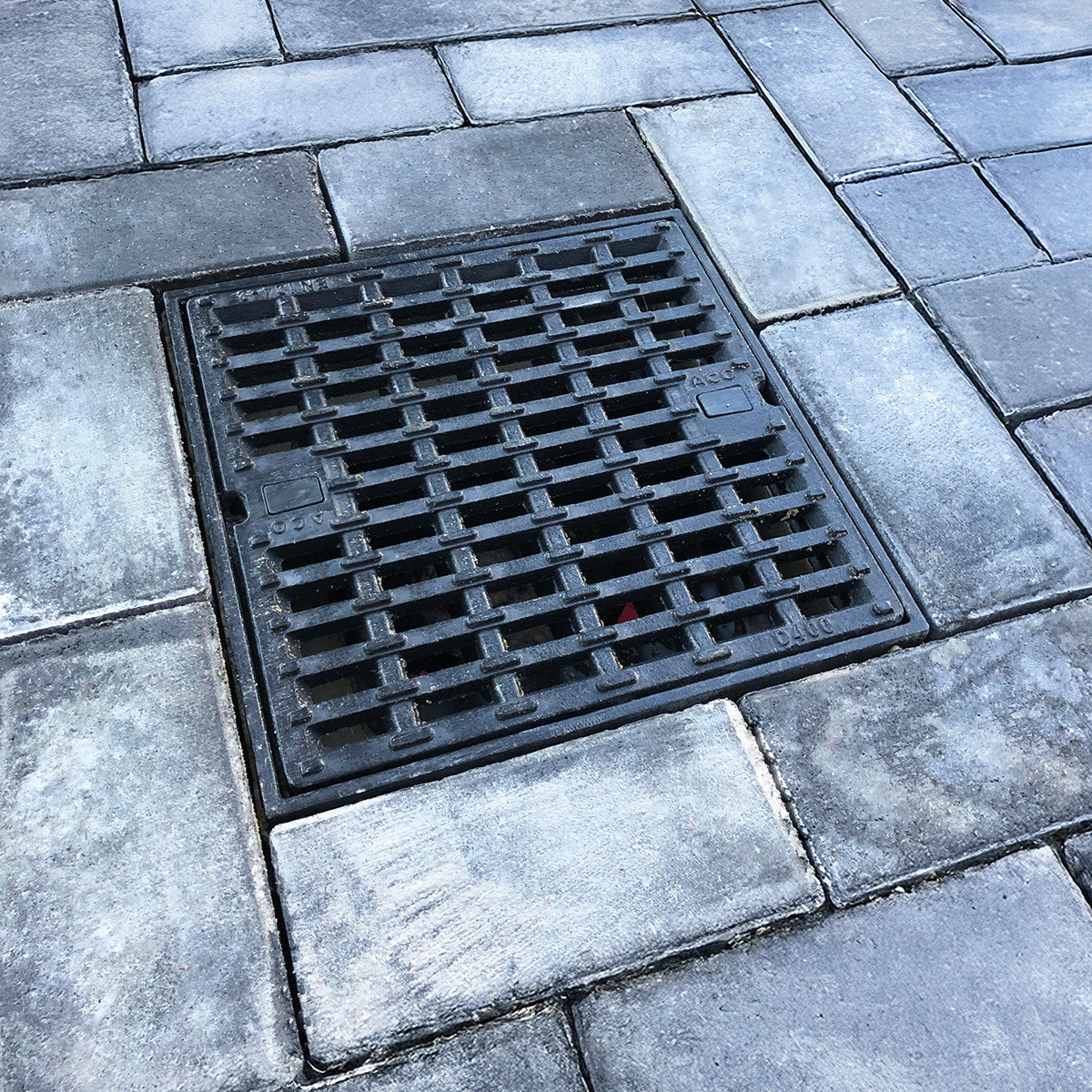 Afvoerput met gietijzeren rooster in betonklinkers